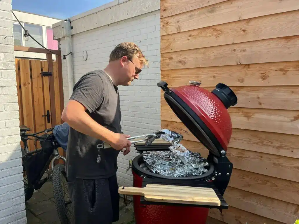 Oprichter van Smokeander bereidt eten op de rode Kamado Joe in de achtertuin